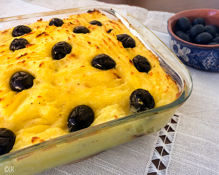 Ovenschotel met goudgele aardappelpuree korst met zwarte olijven en een schaaltje olijven op de achtergrond