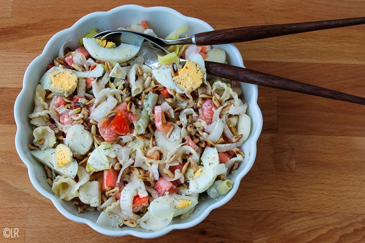 Schaal met een heerlijke maaltijdsalade van pasta, witlof, gerookte zalm en ei.