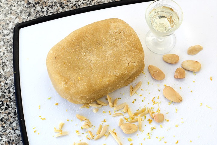 Blok eigengemaakt amandelspijs omringt door amandelen, suiker een een slokje bittere amandellikeur