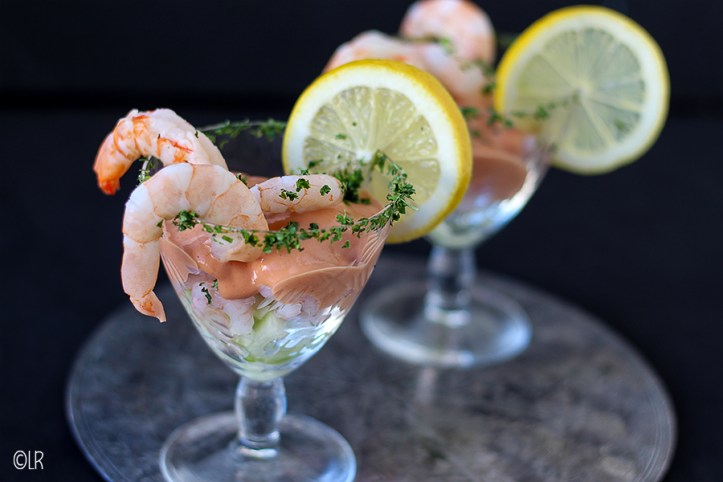 Het is de saus, volgens oud familierecept, die deze cocktail zo verrassend maakt. 2 cocktails met garnalen, komkommer en langoustines gedecoreerd met gehakte peterselie en een schijfje citroen.
