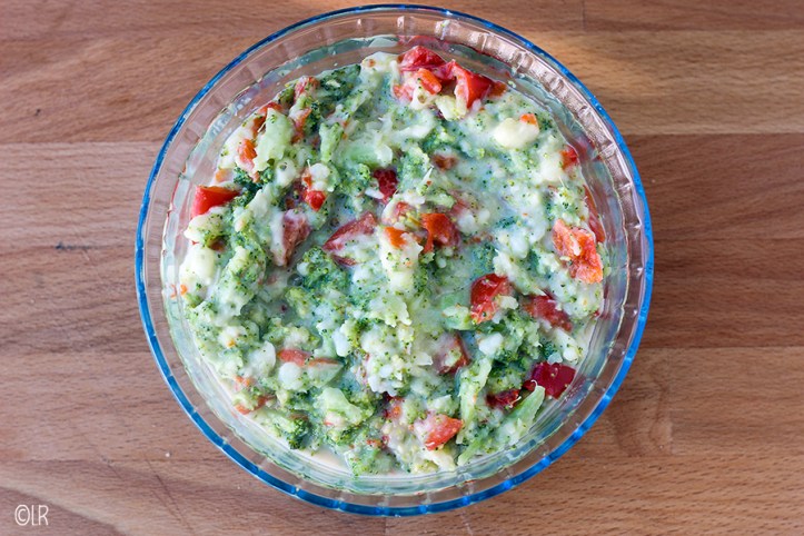 Schaal met kleurige grove broccolistamppot met stukjes paprika.