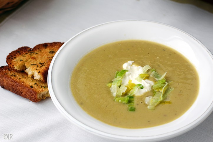 bord met volle romige preisoep gemaakt met zoete aardappel en een toefje feta-crème. Ernaast twee bruschetta's van oud brood met knoflook 