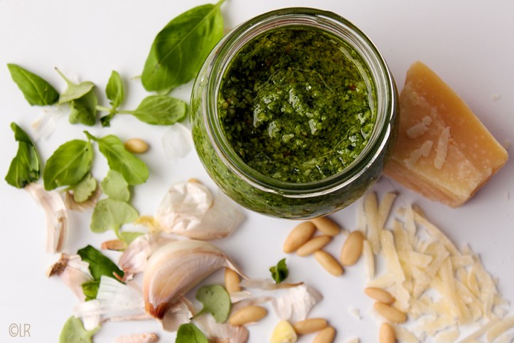 Een echte klassieker deze eigengemaakte basilicumpesto. Potje pesto temidden van de gebruikte ingrediënten.