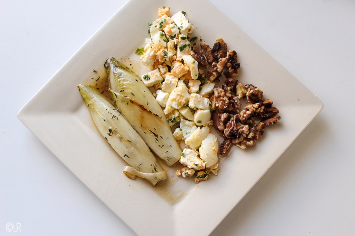 Gesmoorde witlof met ei, feta en walnoten. Mix op het bord door elkaar voor een heerlijke salade.