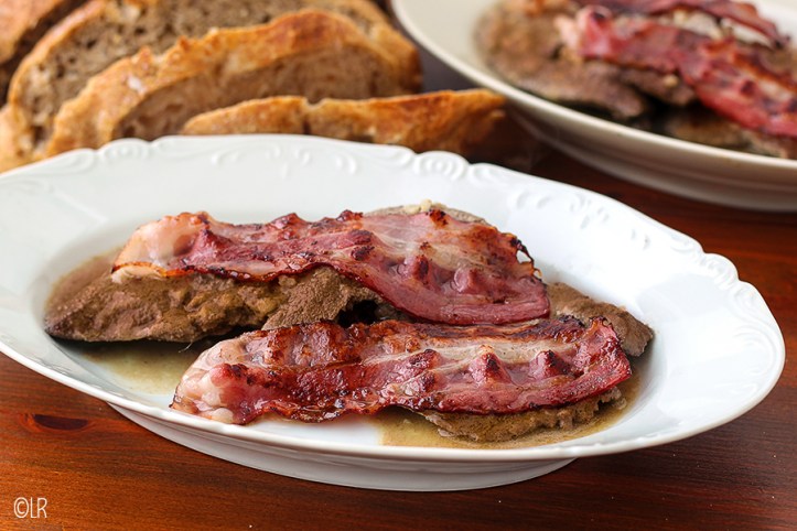 Dun gesneden lever, gemarineerd en gebakken in een knoflook-wijnsaus gebakken bacon Dun gesneden lever, gemarineerd en gebakken in een knoflook-wijnsaus gebakken bacon